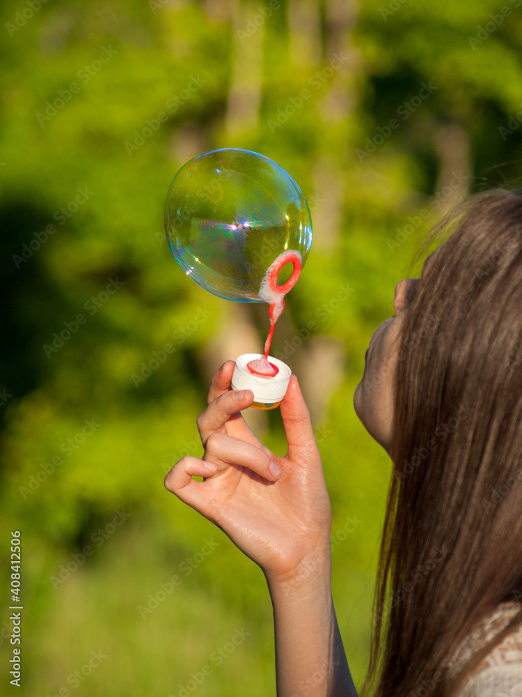 inflate big soap bubbles, girl inflates soap bubbles against the background of the sun, outdoor recreation, park in summer