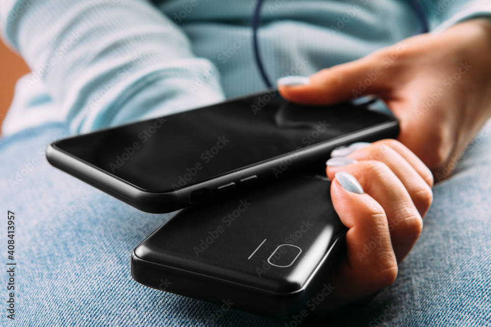 Fototapeta premium The woman plugged the charger with the phone in office or at home. Power Bank.