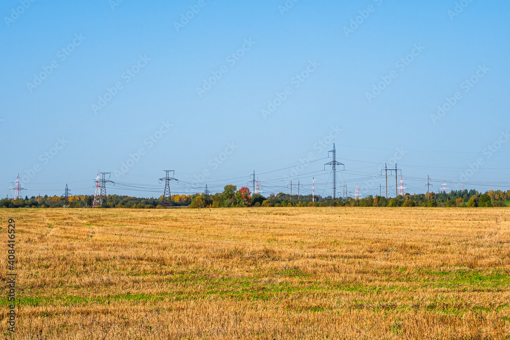Panoramic view of the cell towers standing in a row on the horizon in the autumn field.