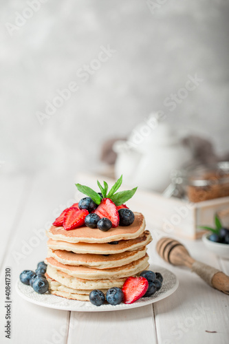 Classic american pancakes with fresh berry on white wood background. Summer homemade breakfast.