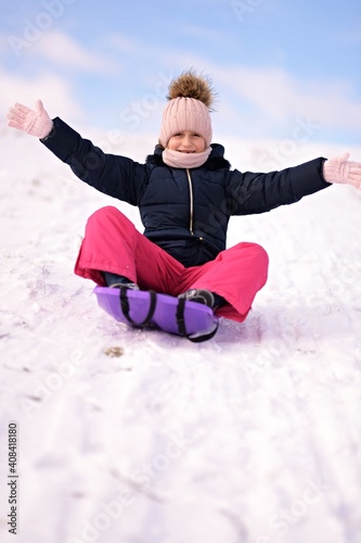 Little girl enjoying a sleigh ride. Child sledding.