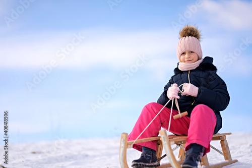 Little girl enjoying a sleigh ride. Child sledding.