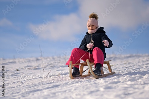 Little girl enjoying a sleigh ride. Child sledding.