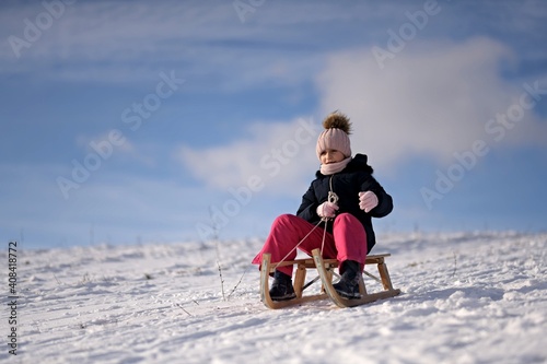 Little girl enjoying a sleigh ride. Child sledding.