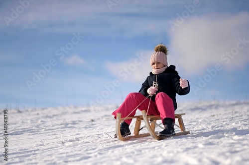 Little girl enjoying a sleigh ride. Child sledding.