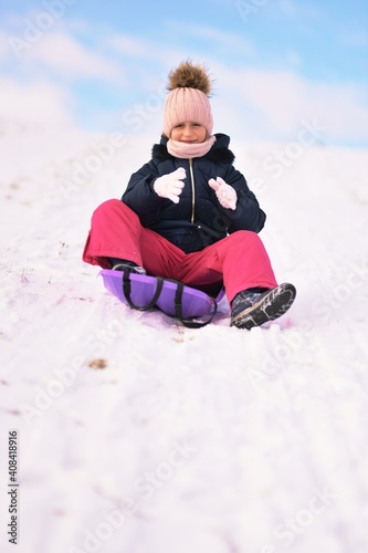 Little girl enjoying a sleigh ride. Child sledding.