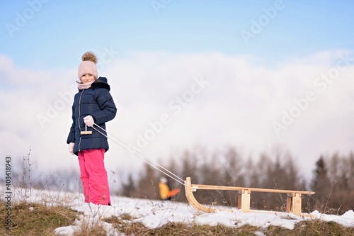 Little girl enjoying a sleigh ride. Child sledding.