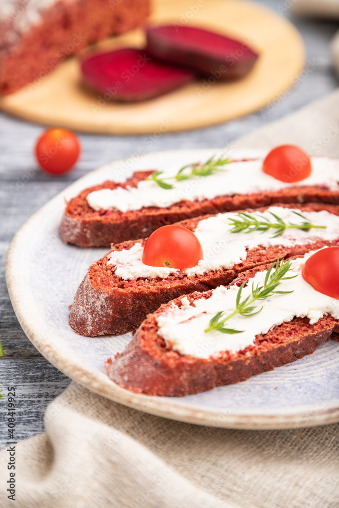 Red beet bread sandwiches with cream cheese and tomatoes on gray wooden background. Side view, selective focus. Red beet bread sandwiches with cream cheese and tomatoes on gray wooden background. Side view, selective focus.