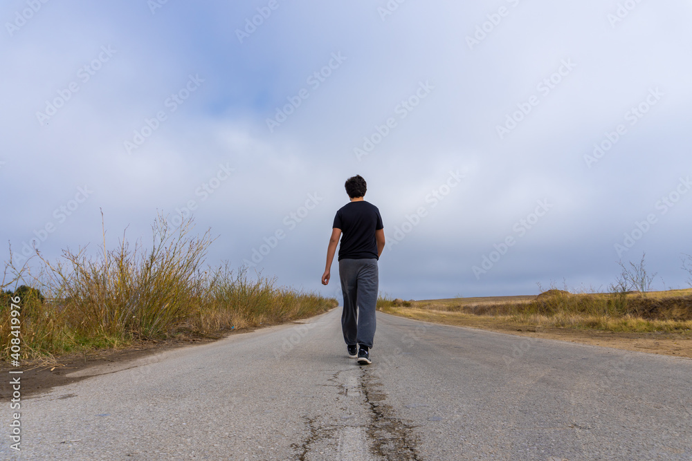 Faceless person walking in a road surrounded by the countryside. Faceless person walking in a road surrounded by the countryside.