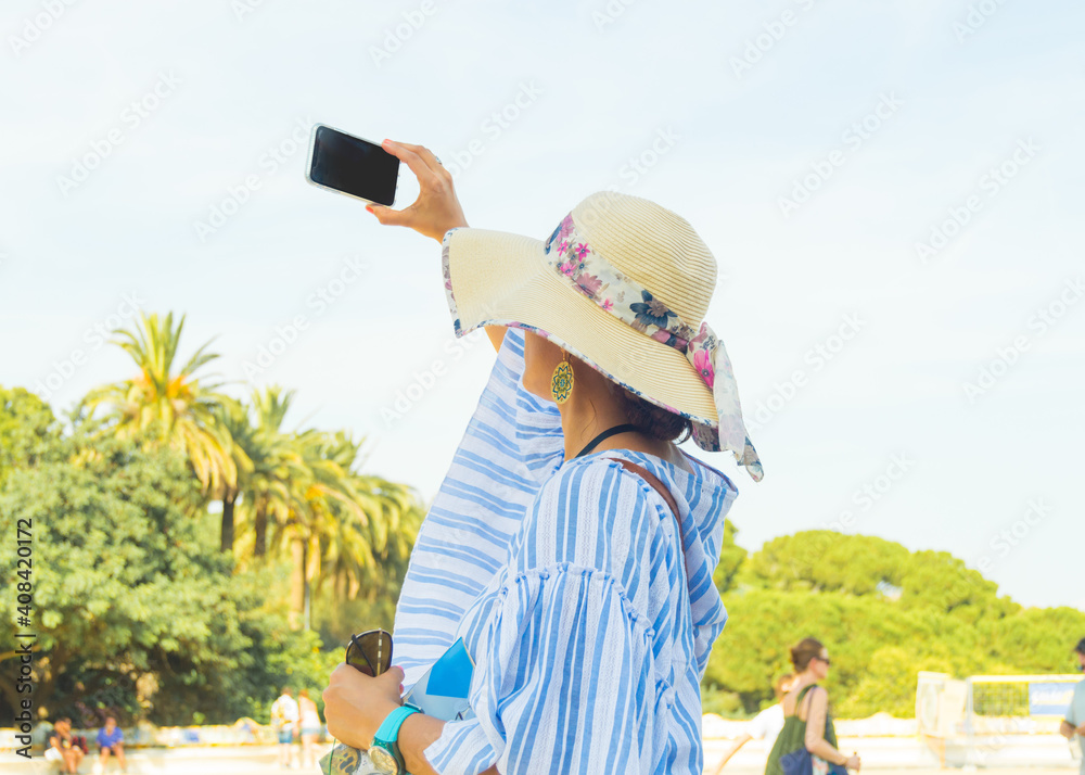 Elegant woman tourist taking photos with her smartphone in a turistic place.