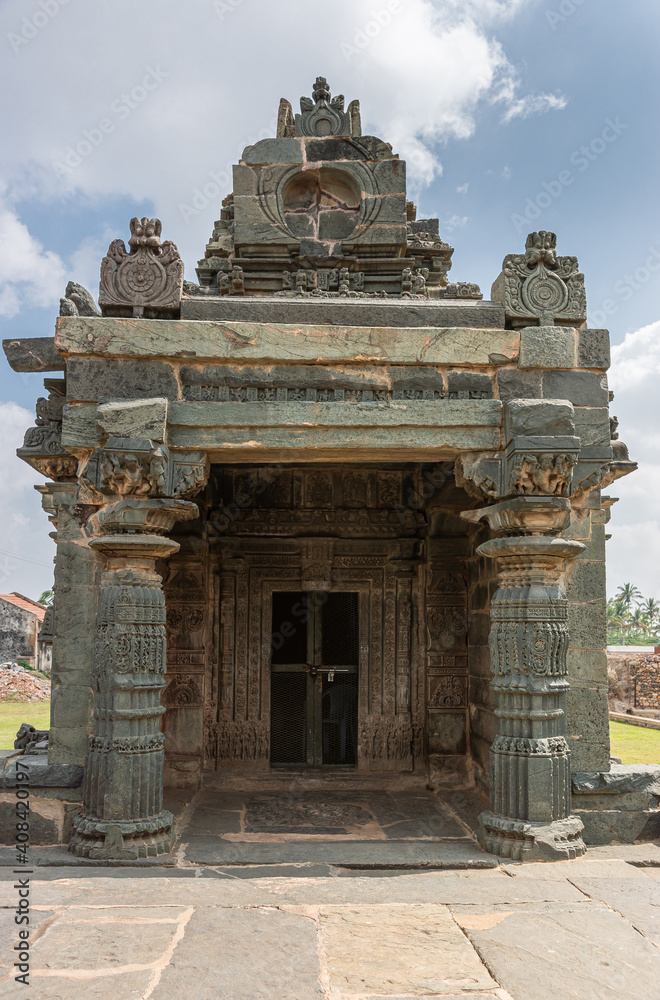 Lakkundi, Karnataka, India - November 6, 2013: Kasivisvesvara Temple. Closeup of locked stand-alone Surya shrine, greenish bray construction under blue cloudscape.
