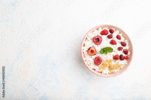 Rice flakes porridge with milk and strawberry in ceramic bowl on white concrete background. Top view, copy space.