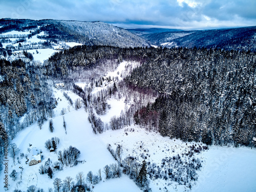 Beautiful panoramic aerial drone view on a winter landscape in the Stolowe mountains during a snowfall. The Stolowe Mountains National Park, Poland, Europe