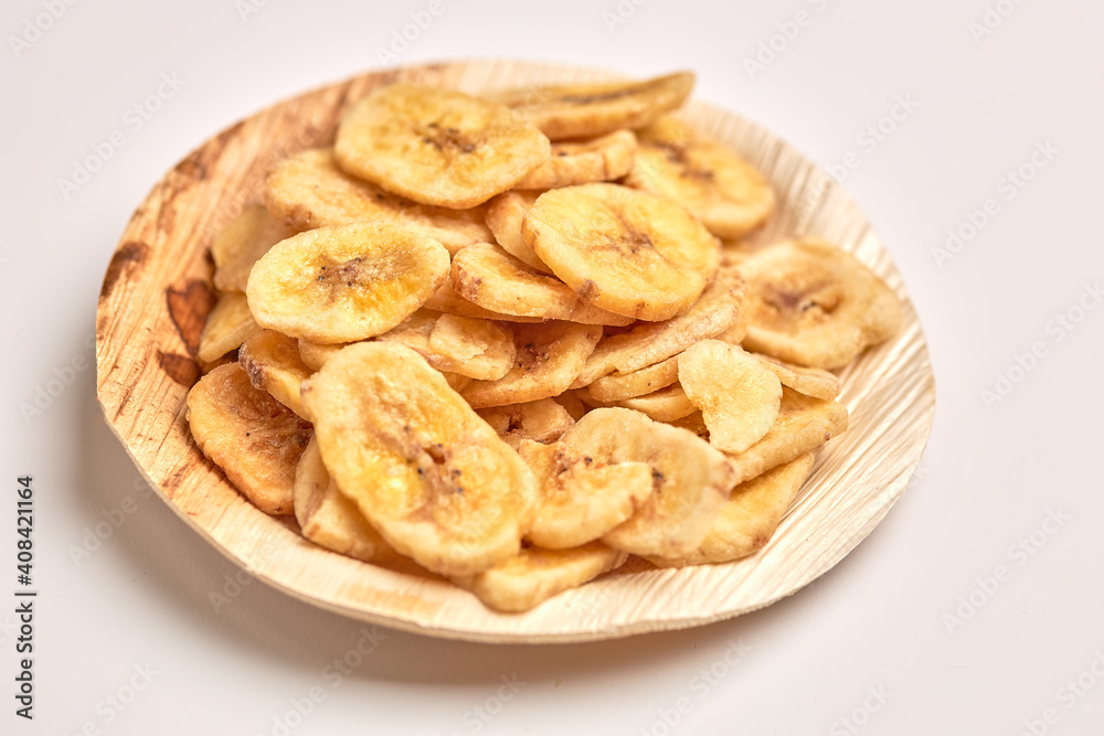 Dehydrated banana in wooden plate isolated on white background.