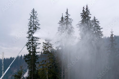 Snow cannon throwing Producting Snowon slope, snowmaker in action at ski resort photo