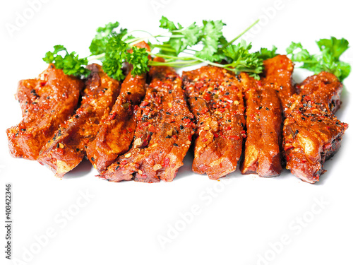Uncooked raw marinated style pork belly chops on a white background with coriander leafs. Korean style marinade over the slices. Meat industry product