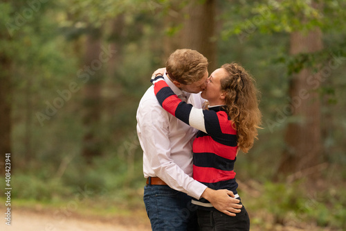 Beautiful young couple, is kissing in the forest. Arms around each other. Man and woman in half body