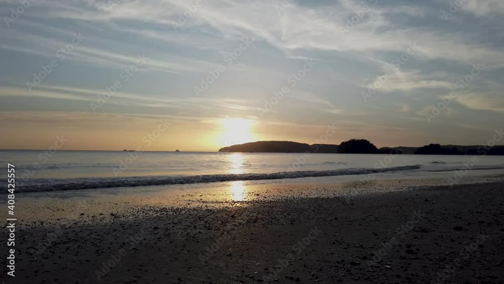 Woman on a sandy beach in the evening in Thailand cleaning her shoes in the ocean with the sunsetting in the background, the beach is known as Hat Noppharat Thara in Ao Nang area of Krabi in Thailand Woman on a sandy beach in the evening in Thailand cleaning her shoes in the ocean with the sunsetting in the background, the beach is known as Hat Noppharat Thara in Ao Nang area of Krabi in Thailand