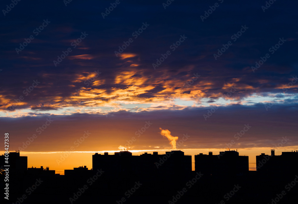 Fantastic sunset with bright red sky and futuristic clouds over the city. .Urban profile with silhouettes of houses on the background of the sunset sky. Place for your text.