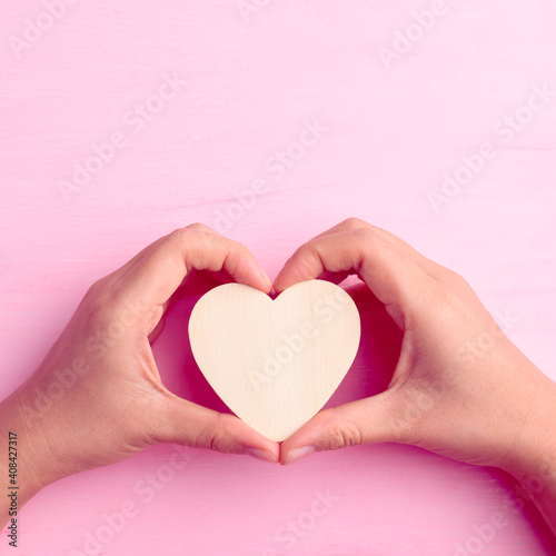 Hand holding heart shape on pink background, Valentine day