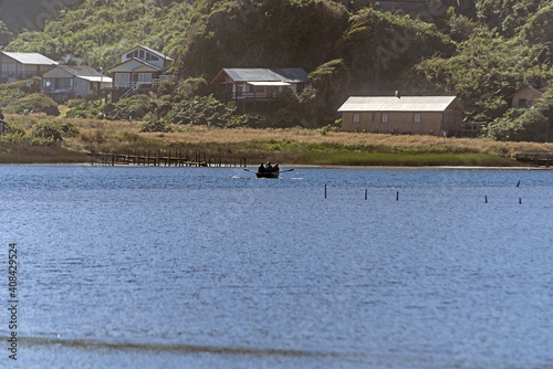 Silhouette of a boat in the lake with village scenery in the background photo