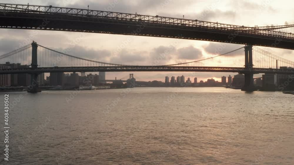 Flight below under Brooklyn Bridge towards Manhattan Bridge at beautiful Scenic Sunrise in New York City