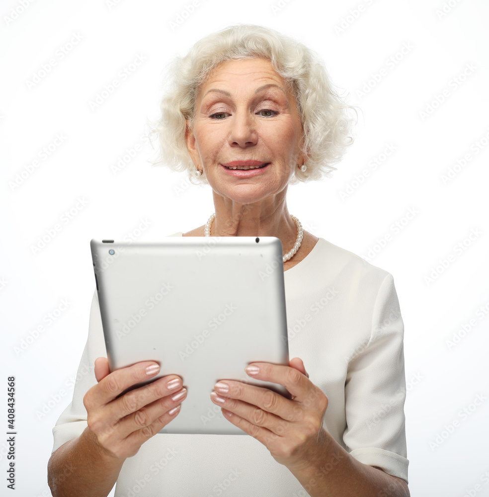 Lifestyle, tehnology and old people concept: Modern middle-aged grandmother using tablet, contemporary elderly mature woman browse Internet on pad over white background Lifestyle, tehnology and old people concept: Modern middle-aged grandmother using tablet, contemporary elderly mature woman browse Internet on pad over white background