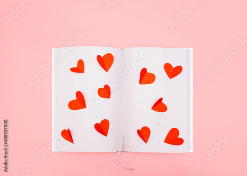 Valentine's Day concept Top view photo in minimal style Cutted red paper hearts on empty silver sheets of notepad