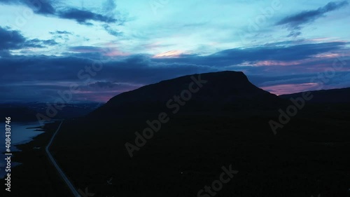 Aerial view of the silhouette of the Saana fell, colorful, summer evening, in Kilpisjarvi, Lapland, Finland - pull back, drone shot photo