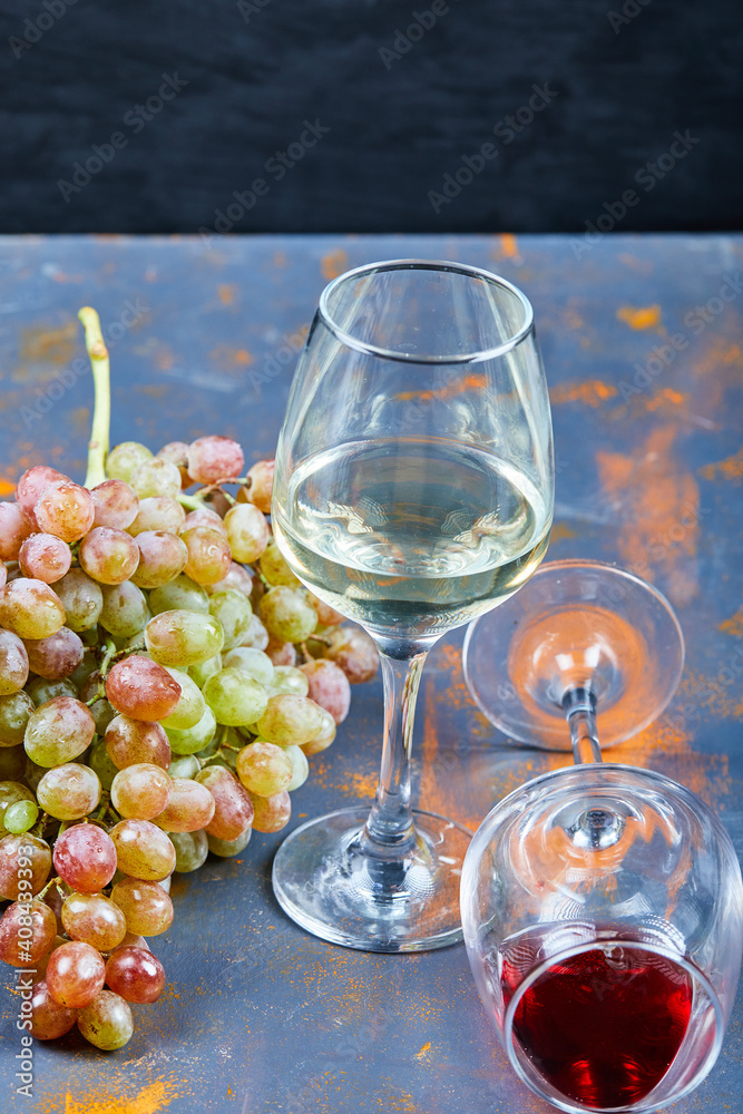 Bunch of grapes and glasses of wine on blue background