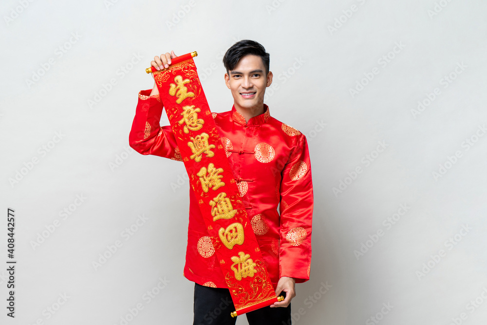 Handsome smiling Asian man showing red label in isolated studio light gray background for Chinese new year concepts, text means prosperous business Handsome smiling Asian man showing red label in isolated studio light gray background for Chinese new year concepts, text means prosperous business