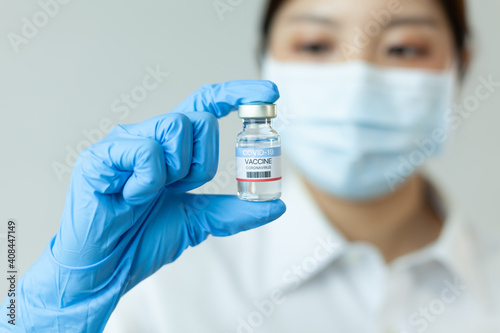 COVID-19 vaccine concept of fight against coronavirus. Doctor in medical gloves holding a coronavirus vaccine bottle.