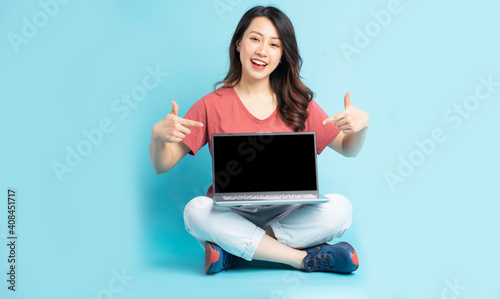 Beautiful Asian woman sitting pointing at the laptop © Timeimage