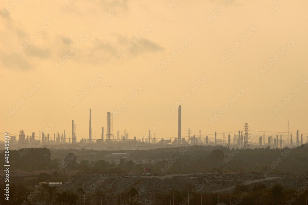 Industrial city skyline of factory towers against an orange sunset sky Industrial city skyline of factory towers against an orange sunset sky
