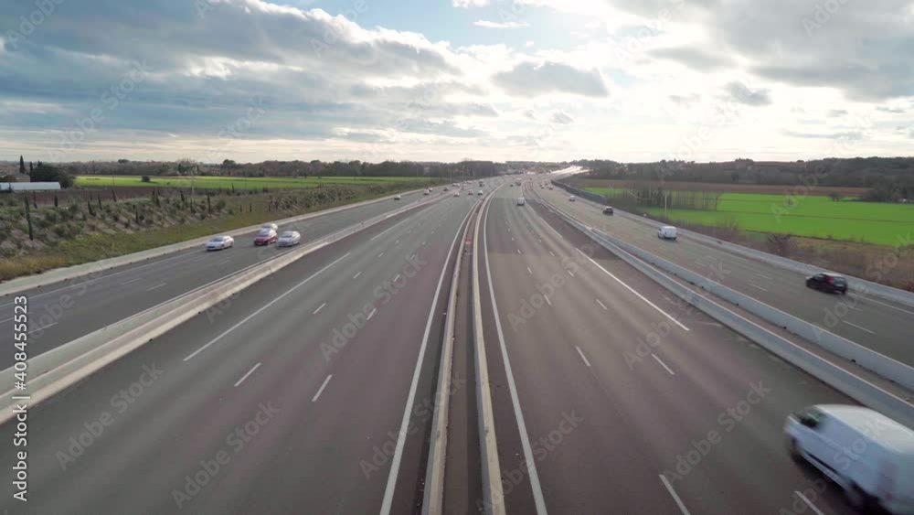 Looking at cars passing by on a quiet highway from above, beautiful horizon with blue sky and clouds Looking at cars passing by on a quiet highway from above, beautiful horizon with blue sky and clouds