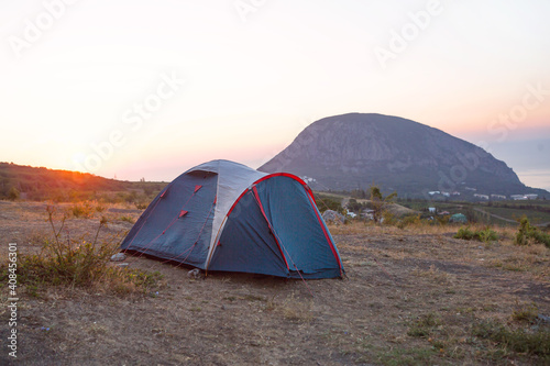 Installed tourist tent in the mountains with a view of the sea and sunrise. Domestic tourism  active summer trip  family adventures. Ecotourism  camping  sports mountain hiking. Ayu-Dag  Crimea.