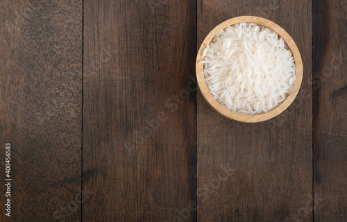 Jasmine rice in wooden bowl on grunge wooden table background with copy space,top view