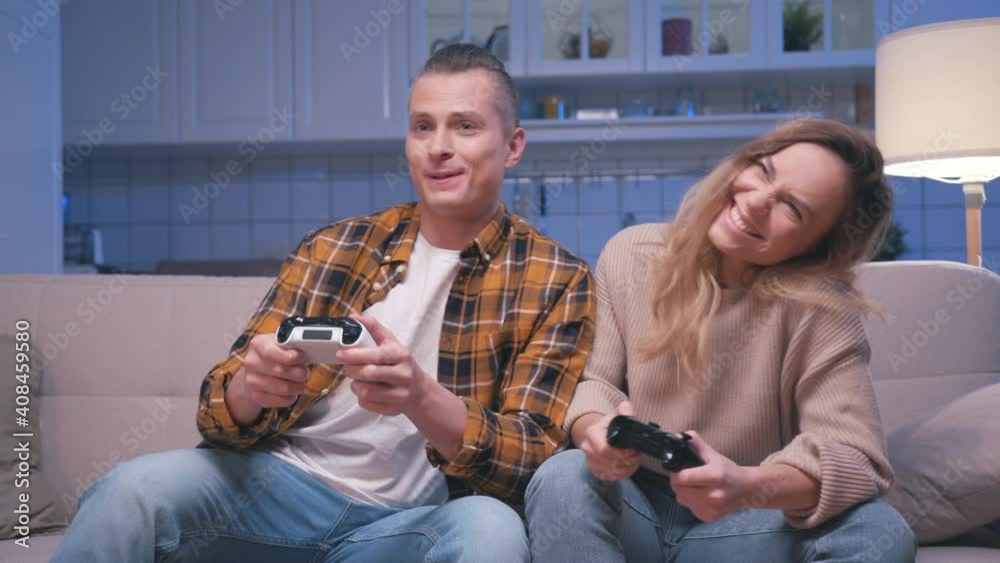 Action Gamers Young Man and Woman Sitting on Sofa and Playing Video ...