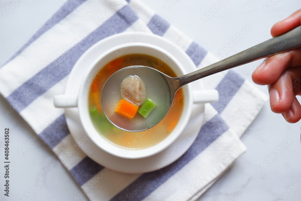 vegetable soup in a spoon from a bowl on a white background vegetable soup in a spoon from a bowl on a white background