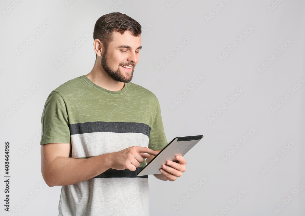 Young man with tablet computer on light background Young man with tablet computer on light background