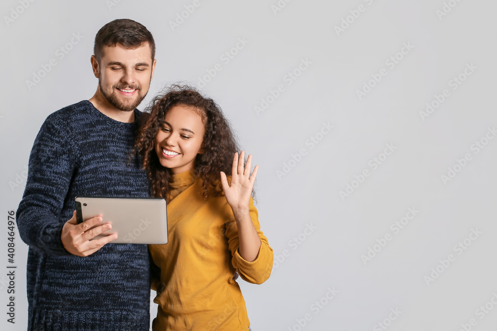 Young couple with tablet computer on light background Young couple with tablet computer on light background