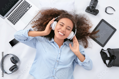 Young woman with different gadgets in headphones on white background photo