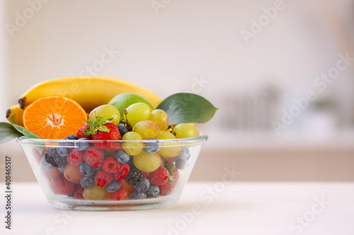 Bowl with different fruits and berries on table