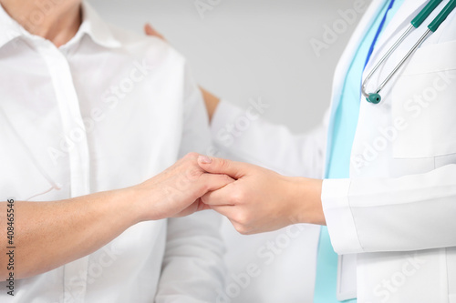 Hands of doctor and mature woman undergoing chemical therapy course in clinic