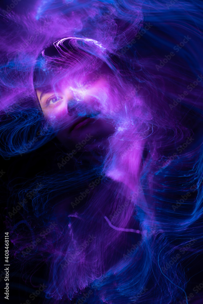 Portrait of young woman amid light painting , Over Black Background. Long exposure photo without photoshop, light drawing at long exposure