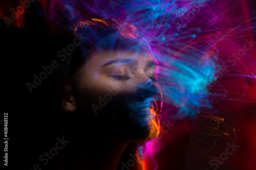 Portrait of young woman amid light painting , Over Black Background. Long exposure photo without photoshop, light drawing at long exposure
