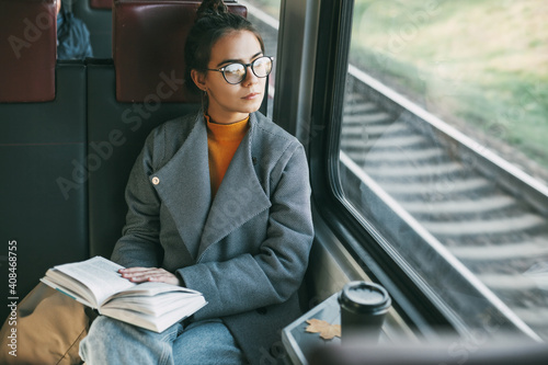Young beautiful girl on a train reading a book while traveling in a train
