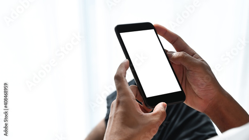 Close up view of man hands holding smart phone with white screen. Blank screen for your text message or information content.