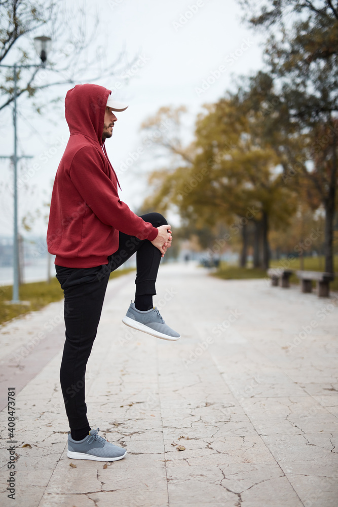 Fototapeta premium Athletic sporty man training in hoodie sweatshirt in urban city park.