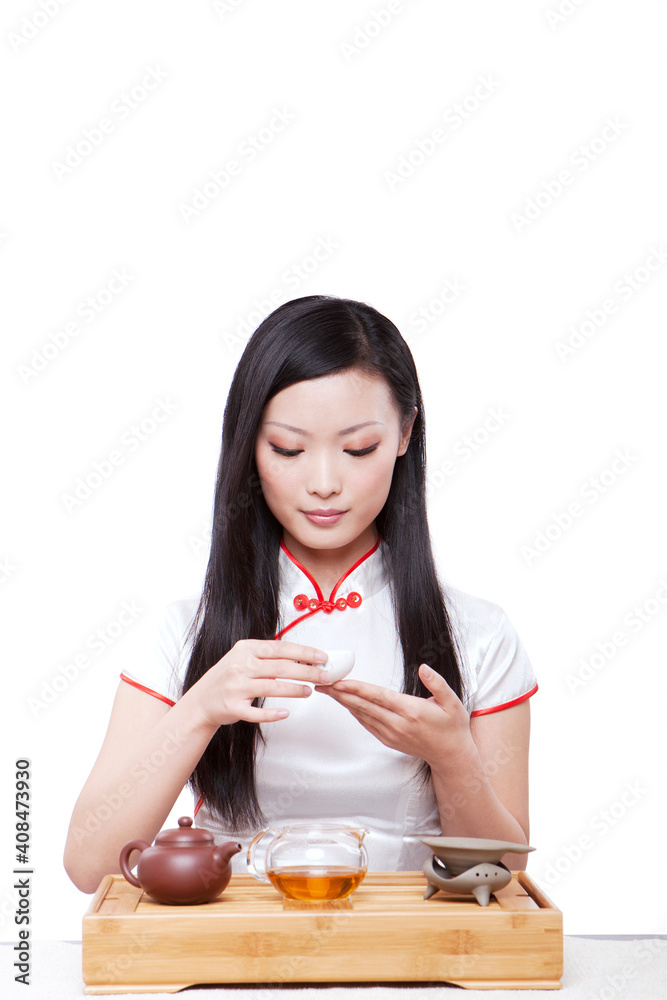 Wearing cheongsam Oriental young woman in preparation for the tea ceremony Wearing cheongsam Oriental young woman in preparation for the tea ceremony